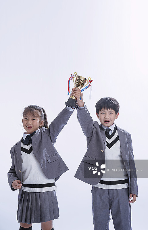 两个小学生举起奖杯图片素材