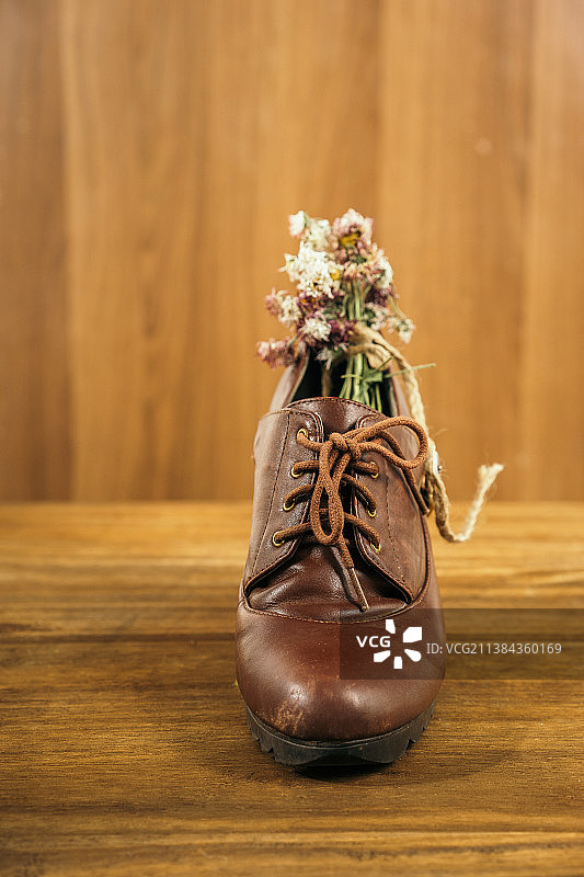 一只褐色女式皮鞋里插着干燥花料图片素材