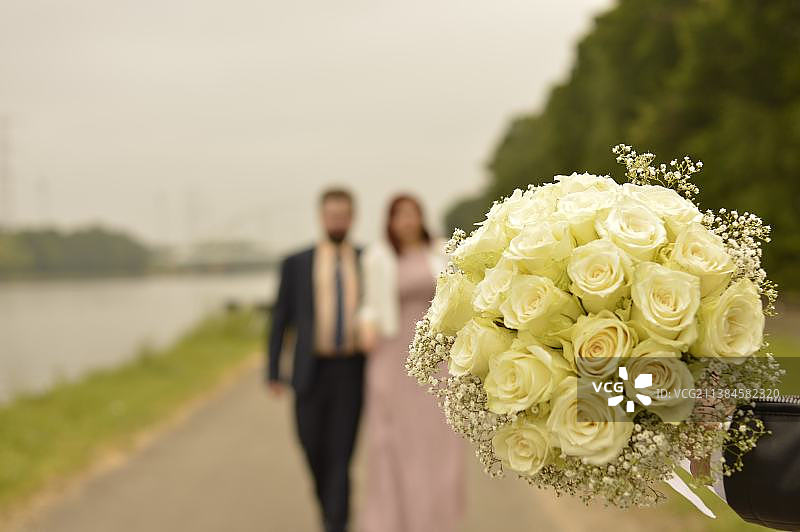 婚礼，新娘和新郎手捧花束站在天空下的特写图片素材