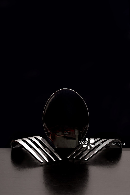 黑色背景下餐桌上的勺子和叉子特写图片素材