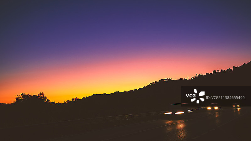 日落时分，行驶在道路上的汽车剪影图片素材
