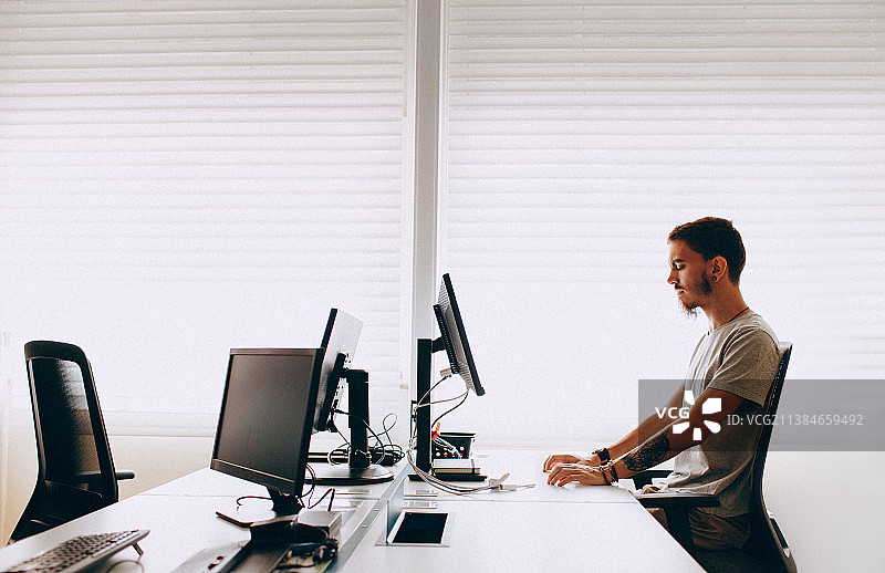 年轻男程序员在办公室的电脑上工作，巴西米纳斯吉拉斯州贝洛奥里藏特图片素材