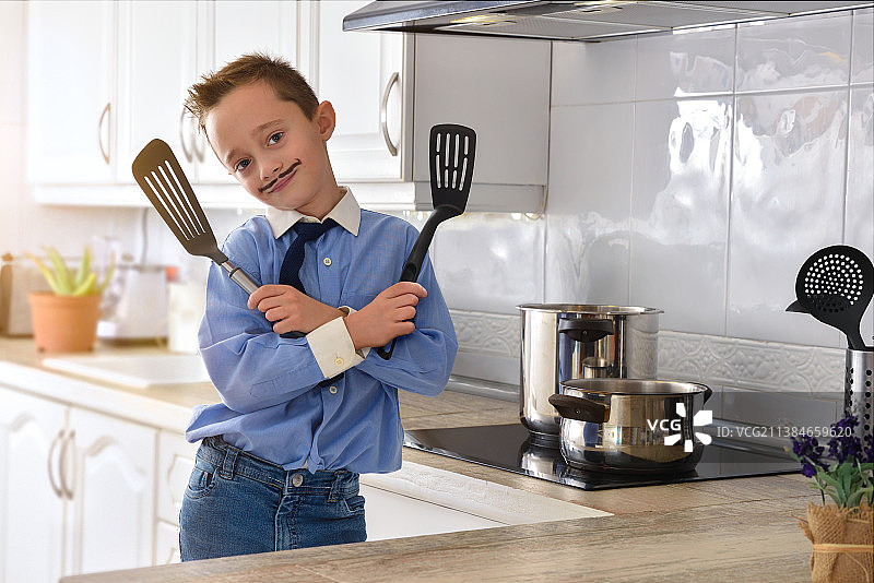 在白色厨房里手拿锅铲的儿童图片素材
