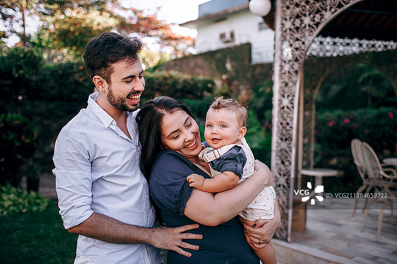 幸福的父母和宝贝儿子在后院玩耍和拥抱的合影，巴西米纳斯吉拉斯州贝洛奥里藏特图片素材