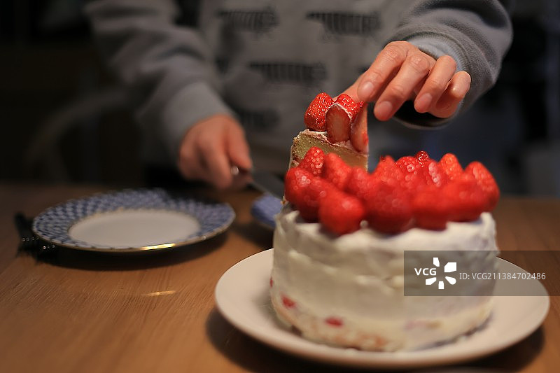 自制圣诞蛋糕，女人在桌子上切蛋糕的截面图图片素材