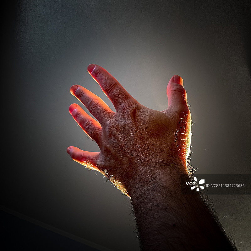 灰色背景上手持发光物体的特写图片素材