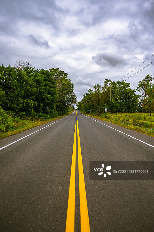 加拿大安大略省大纳帕尼的树木与天空之间的空旷道路图片素材