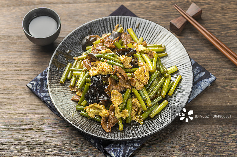 一盘蒜苔鸡蛋炒肉片特写木桌面背景图片素材