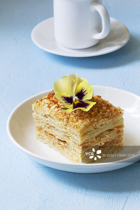 一块拿破仑蛋糕，用三色堇装饰，搭配一杯咖啡或茶图片素材