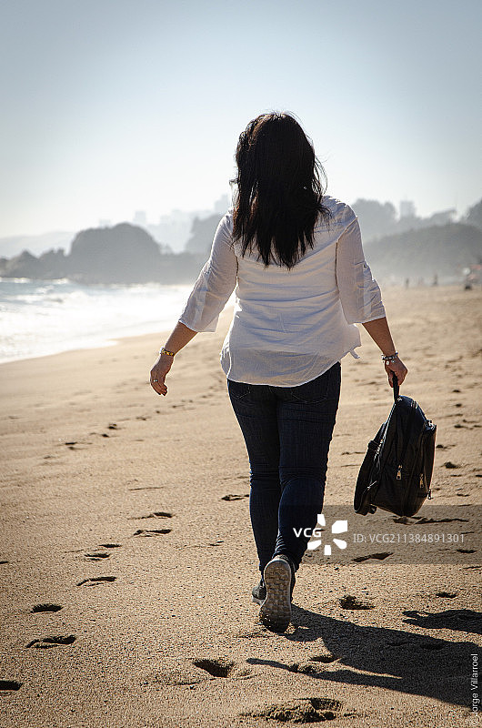 家人共度时光：女子在智利海滩漫步图片素材