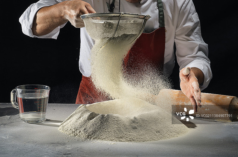 厨师用筛子筛面粉，准备食物的局部图片素材