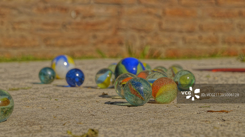 泥土上弹珠玩具特写，背景为砖墙图片素材