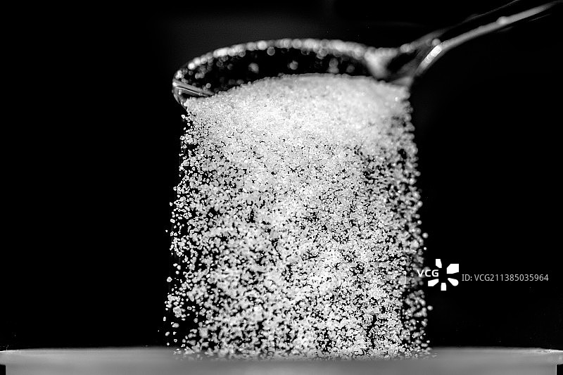 勺子里的糖特写，黑色背景图片素材