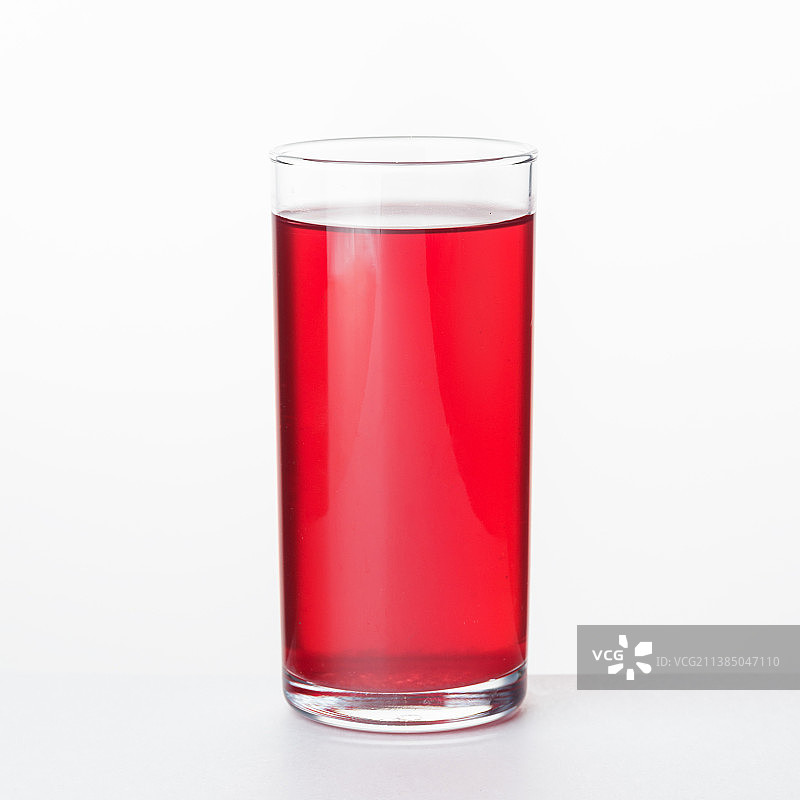 简约红果汁玻璃杯特写，白色背景图片素材