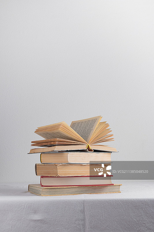 白色桌子上堆叠的旧式乡村复古书籍图片素材