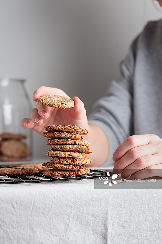 自制燕麦饼干堆叠，女性在桌上准备饼干图片素材