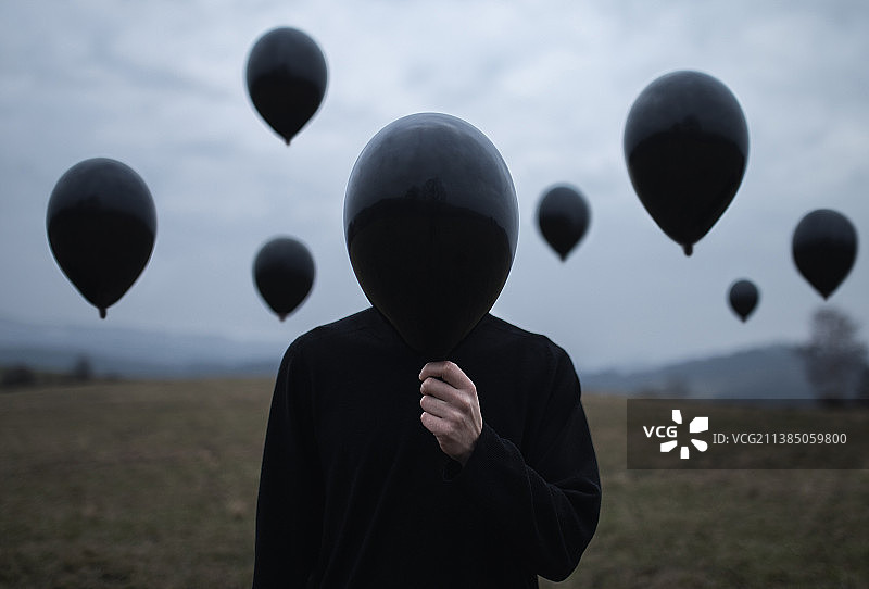 空洞的想法回忆，站在田野上对着天空的男人的轮廓与气球图片素材
