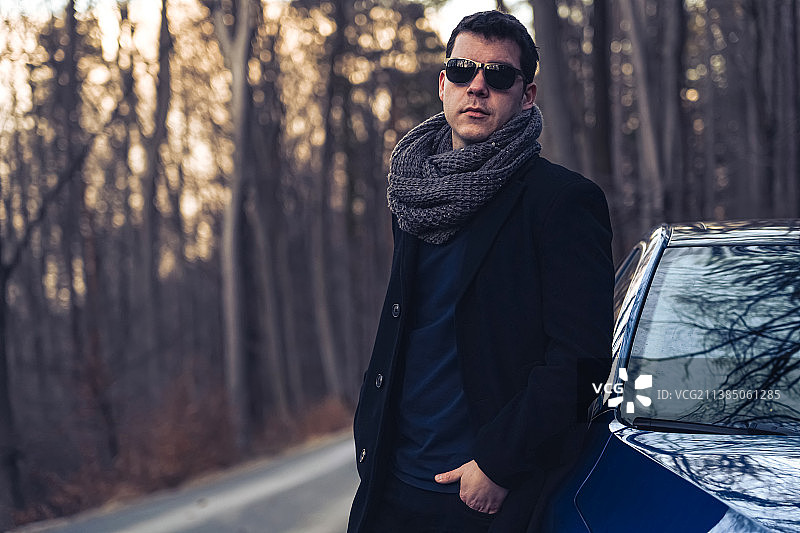 尝试新视角：站在车旁的戴墨镜男子，匈牙利索普朗图片素材