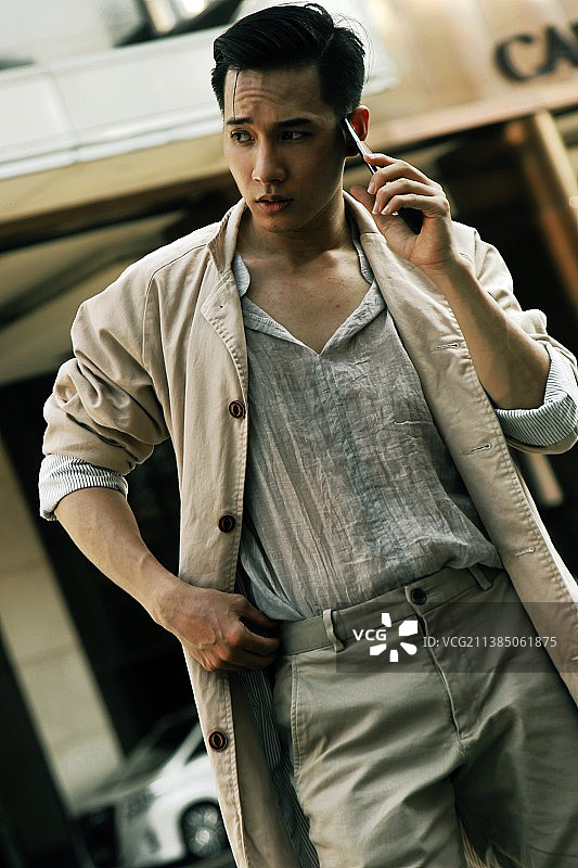 身着时尚服装，在越南用手机交谈的年轻男子肖像图片素材