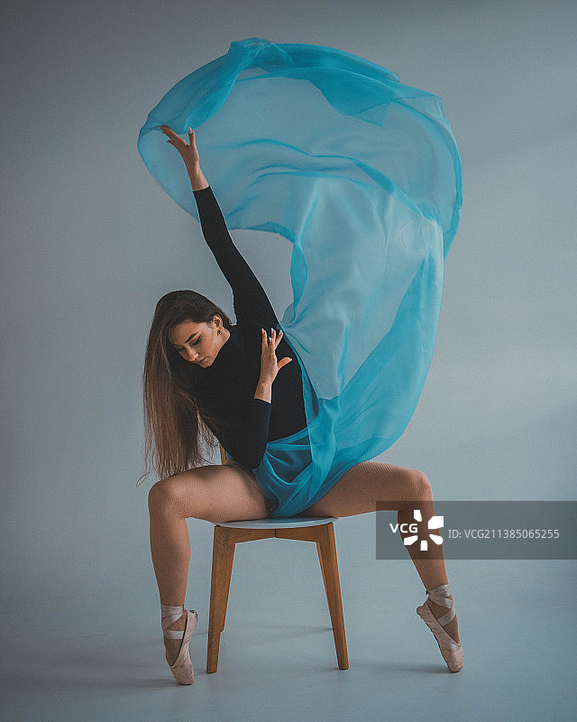 身穿蓝色连衣裙，坐在椅子上的年轻女芭蕾舞演员图片素材