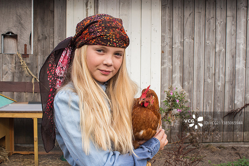 农场里的女孩，抱着一只鸡的肖像图片素材