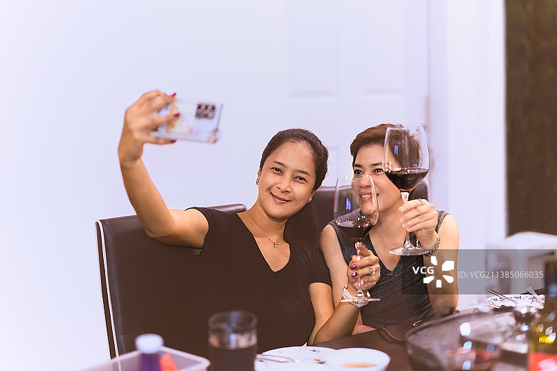 美女们用手机自拍，手里拿着玻璃杯图片素材