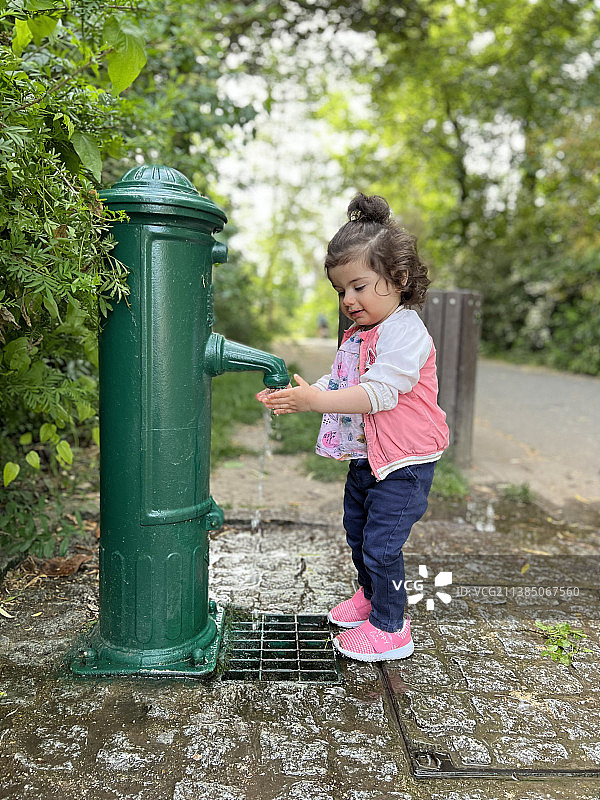 从喷泉喝水的女孩全身照图片素材