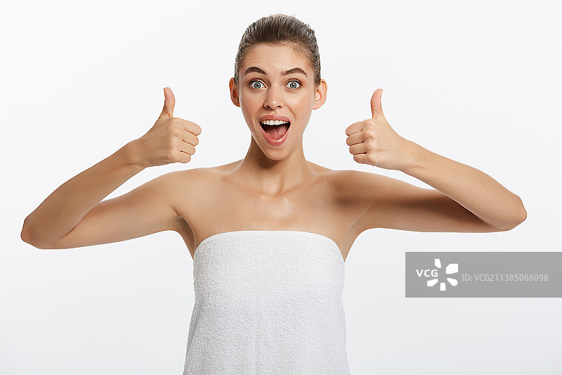 用毛巾擦拭身体并竖起大拇指的年轻女子图片素材