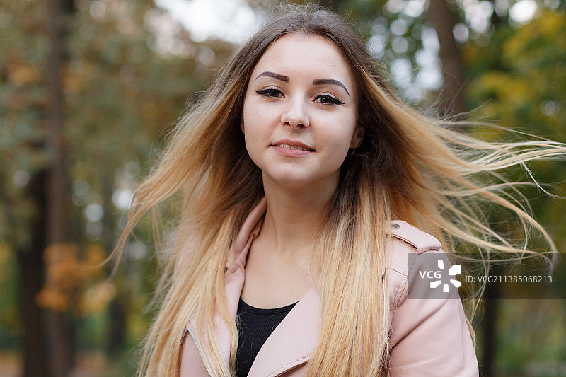 白天站在乌克兰田野树木前的年轻女子肖像图片素材