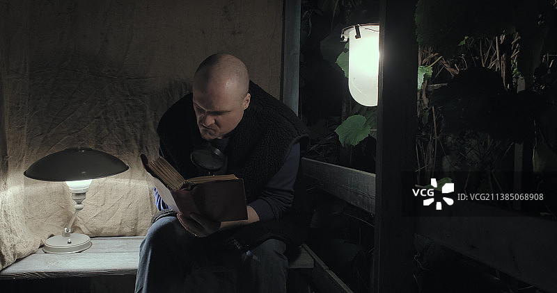 夜晚坐在门廊读书的愤怒老人图片素材