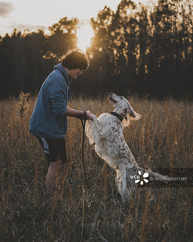 在北卡罗来纳州沃克斯肖，夕阳下玩耍的少年和他的狗图片素材