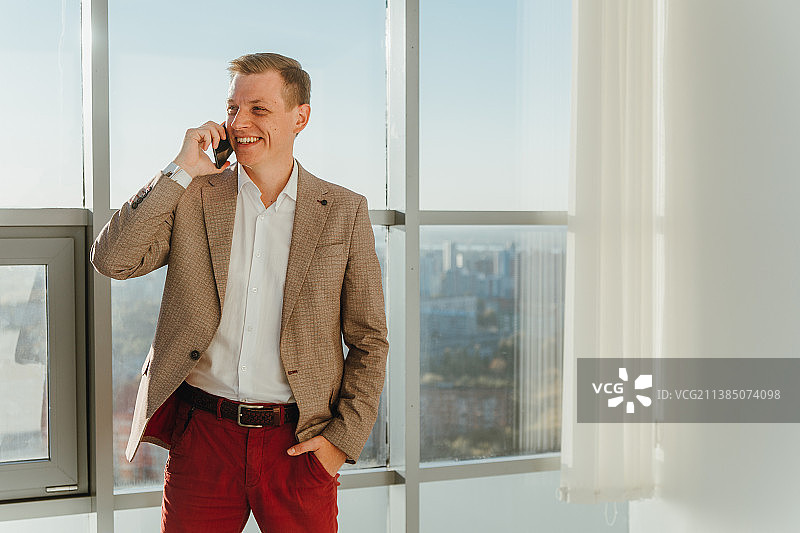 在办公室用手机交谈的微笑商人图片素材