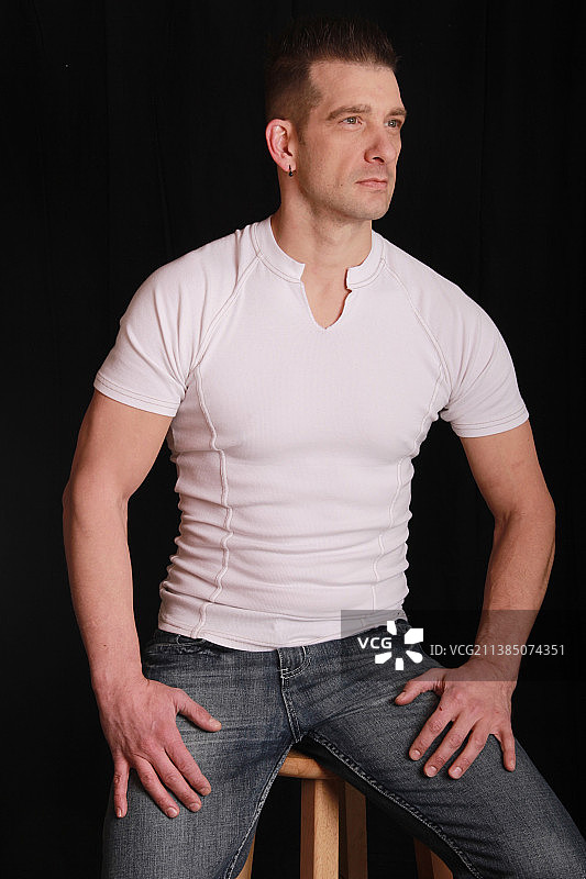 站在黑色背景前向远处看的年轻男人图片素材