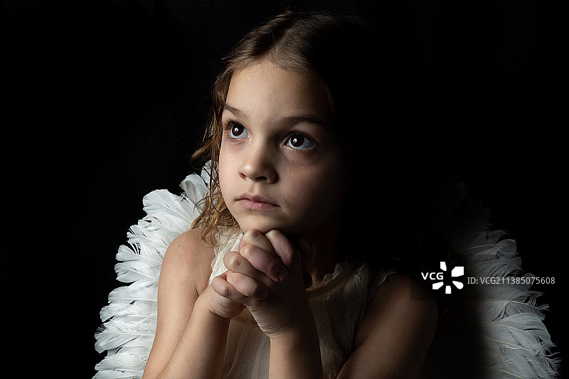 祈祷的天使：佩戴翅膀的可爱女孩，黑色背景图片素材