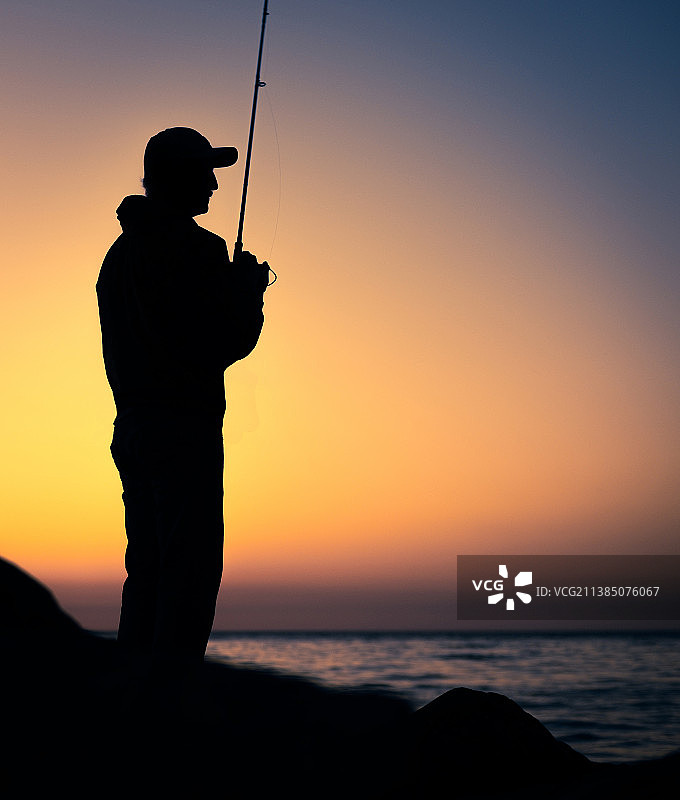 日落时在海边钓鱼的男人剪影图片素材