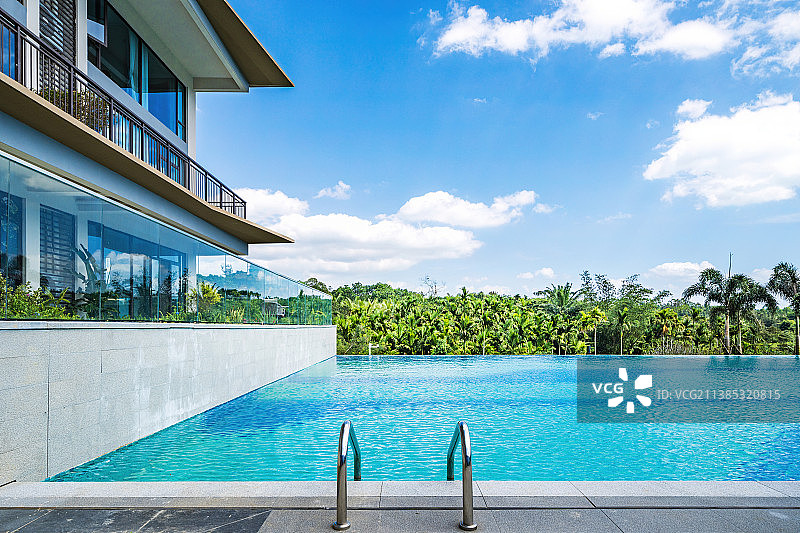 蓝天白云下的游泳池和泳池边的休闲躺椅图片素材