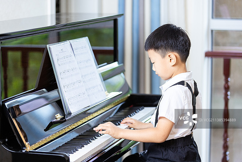 亚洲中国男孩在家里练习弹钢琴图片素材