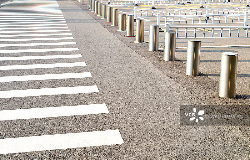 中国城市交通拍摄主题，逆光拍摄黑白相间的斑马线道路和不锈钢升降柱护栏，户外无人图像摄影图片素材