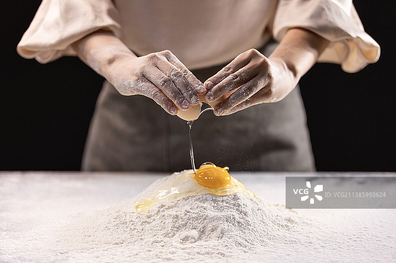 女人在面粉里打鸡蛋特写，准备和面图片素材