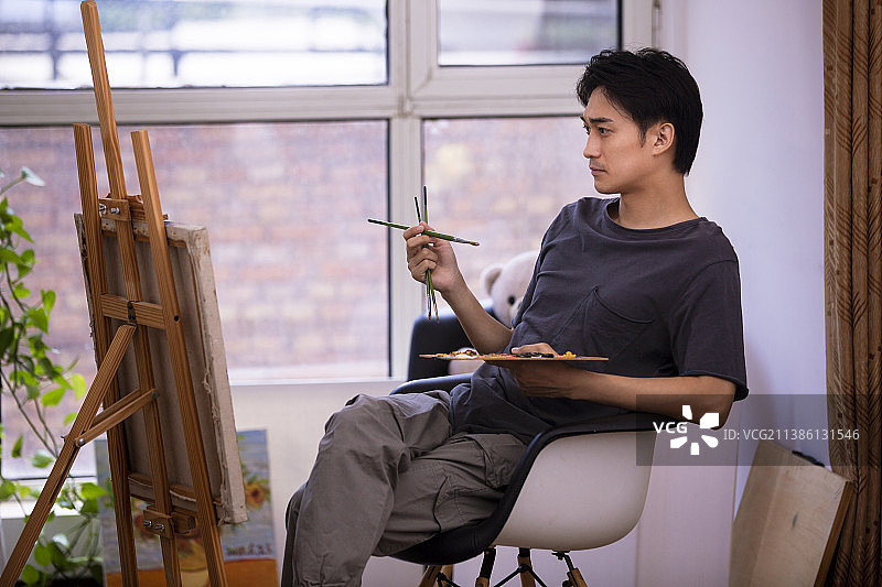 年轻男子在家画油画图片素材