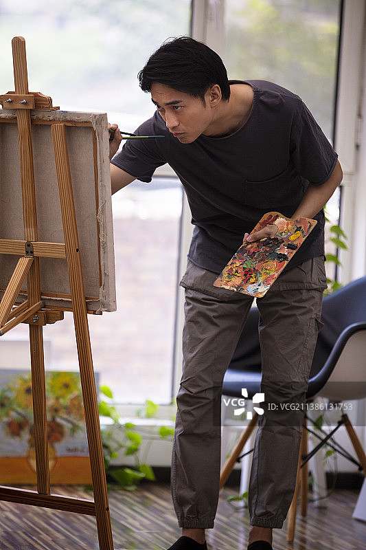 年轻男子在家画油画图片素材