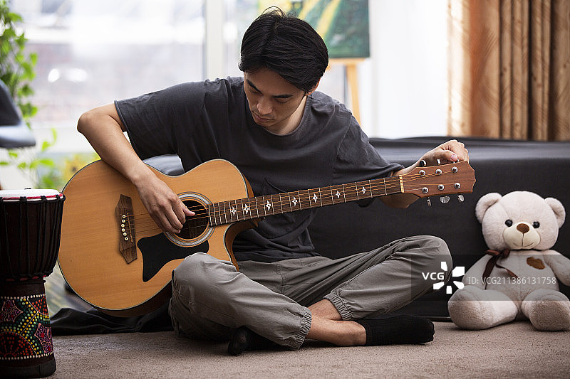 年轻男子在家弹奏吉他图片素材