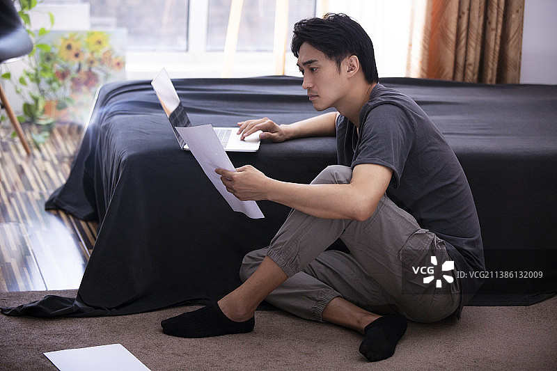 年轻男子在家使用笔记本电脑工作图片素材
