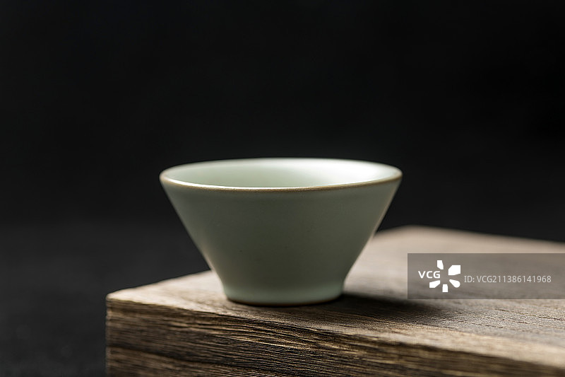 一只汝瓷茶杯茶盏摆放在木桌面上黑色背景图片素材