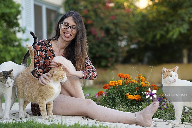 坐在人行道上与猫合影的女子，以色列图片素材