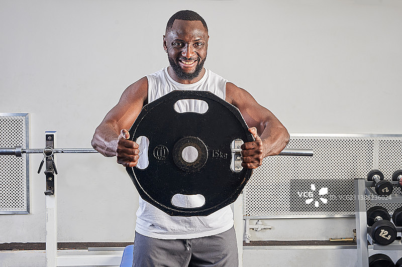 一位在健身房手持金属片的非裔美国男人图片素材