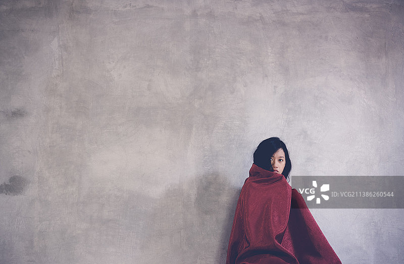 印度尼西亚日惹年轻女人靠墙坐着盖红毯图片素材