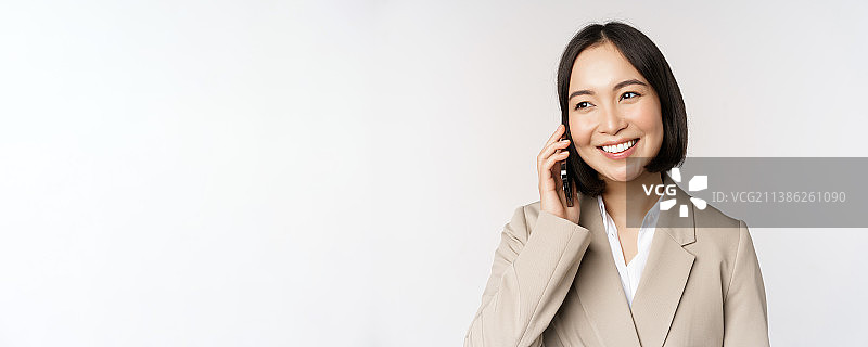 微笑的职业女性穿着西装，正在用手机通话图片素材
