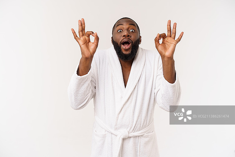 穿着浴袍的年轻非洲男子准备做皮肤护理，展示OK手势图片素材