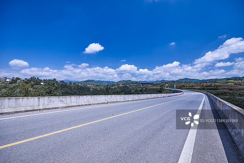 省道230洋县韩家湾路段蓝天白云下的空旷的公路图片素材